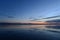 Moonrise in twilight light in the blue sky at sunset over the quiet mirror water of the lake