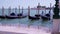 Moored black gondolas swing in azure bay in Venice zoom in