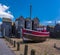 A moored fishing boat rests in front of the net drying sheds in the old town of at Hastings, Sussex, UK