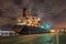 Moored oil tanker at night with a dramatic cloudy sky, Port of Antwerp, Belgium.