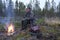 Moose hunter sitting on a stump with a litle fire in front.