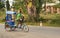 Moramanga, Madagascar - April 25, 2019: Young boy riding traditional bicycle rickshaw, large blurred house in background. These