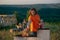 A more chubby handsome man with a bright orange shirt is holding a beer and warming up the outside grill with oil while