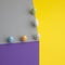 More colorful eggs and a white heart on a paper cube on a yellow background. Minimal Easter scene