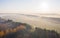 Morning autumn fog creeps over fields and tree plantations, aerial photography