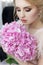 Morning of a beautiful tender sweet bride in a boudoir dress with a bouquet of hydrangea flowers with an evening hairdo and bright