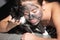 Morning with black cat. Woman with charcoal facial mud mask on face. Cosmetic procedure. Beauty spa and cosmetology. Spa