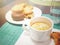 Morning breakfast with a cup of frothy cappuccino with pastry and chocolate donuts