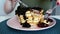 Morning breakfast in foreground view. Woman eating berries pancakes with knife and fork