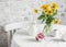Morning breakfast table - greek yogurt with raspberries, bouquet of yellow flowers on a light table. Cozy kitchen still life