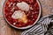 Morning breakfast. Tomato shakshouka with two poached eggs on a plate. Crispy sourdough bread on the side. Coffee in french press