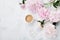Morning coffee and beautiful pink peony flowers on white stone table top view in flat lay style. Cozy breakfast on Mother day.