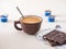 Morning coffee in ceramic mug and chocolate bar, disposable cream