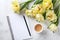 Morning coffee, clean notebook and beautiful bunch of tulip flowers on white stone table top view. Flat lay. Cozy breakfast.