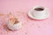 Morning coffee cup and sweet pink donut biscuits c fancy color on pink pastel table top view. Flat lay. Cozy and warm breakfast