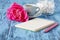 Morning coffee mug, empty notebook, pencil and white peony flowers on blue wooden table