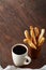 Morning concept with a cup of coffee, breadsticks, fruit pies and oranges on wooden background.