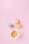 Morning cup of coffee and colorful cake macaron on pastel pink background top view. Cozy breakfast. Fashion flat lay.
