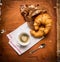 Morning cup of coffee with a heart of foam and croissants, breakfast on rustic wooden background