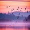 Morning Flight: A Flock of Birds Soaring Over a Colorful Landscape