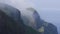 Morning fog drifts through rocky cliffs on Sea of Japan coast as birds fly by