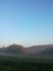 Morning fog on meadow with trees and hills with forest silhouettes