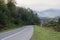 Morning fogy landscape with road through the grassy hills