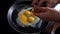 In the morning the girl prepares breakfast at home in the kitchen, breaks eggs in a frying pan. Close-up. Cooking eggs