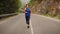 Morning jogging. Woman running on empty mountain road. Fitness activity. Fit female runs in the morning on road surrounded by gree