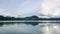 Morning Lake with Blue Water and Mountains with Green Trees and Cloud Reflection