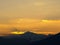 Morning landscape with mountains and orange sky at sunrise with sun reflecting. Evening sunset on the horizon of hills with snow a