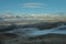 Morning landscape with a river valley, low clouds creeping on the ground and white snowy mountains in the background