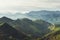 Morning mist in the mountain peaks on natural landscape. Green valley on background foggy dramatic sky. Panorama horizon