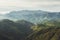 Morning mist in the mountain peaks on natural landscape. Green valley on background foggy dramatic sky. Panorama horizon perspecti