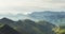 Morning mist in the mountain peaks on natural landscape. Green valley on background foggy dramatic sky. Panorama horizon perspecti