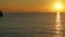 Morning orange sun rising above calm sea, rocky shore on left, timelapse video