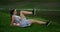 In the morning in the Park, a woman in sports clothes lying on a Mat raises her legs to the body exercise bike