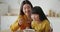 Morning routine at home. Cute loving asian mother feeding her daughter with milk and cereals, sitting at kitchen