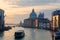 Morning scenery of the Grand Canal bathed in golden twilight, with boats & ferries cruising on waterway & landmark cathedral Basil