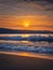 Morning at the sea with vibrant sunrise at horizon and foamy waves hitting the sandy beach