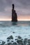 Morning seascape sunrise of Madeira. Rocky shore, silhouette of two steep cliffs and misty rocks hit by waves. Long exposure.