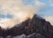 Morning sunlight begins to burn away the clouds that drift across this mountain peak after a winter snow storm