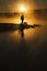 Morning Sunshine and Fog Surround Silhouetted Hiker On Calm Lake