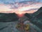 Morning view over crack sandstone edge into forest valley, daybreak Sun at horizon.