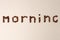 Morning word shaped with coffee beans on gray background, minimal concept