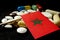 Moroccan flag with lot of medical pills isolated on black background
