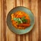 Moroccan food, cous cous dish on a plate with carrot, decorated with mint on a wooden table