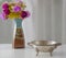 Moroccan metal bowl placed on a table with a vase of flowers.