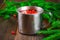 Morse or tea from cowberry in a tin mug, surrounded by fir branches on a wooden table.