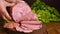Mortadella. Large mortadella with pistachios on a wooden table. A man cuts thin slices of sausage. Traditional meat food